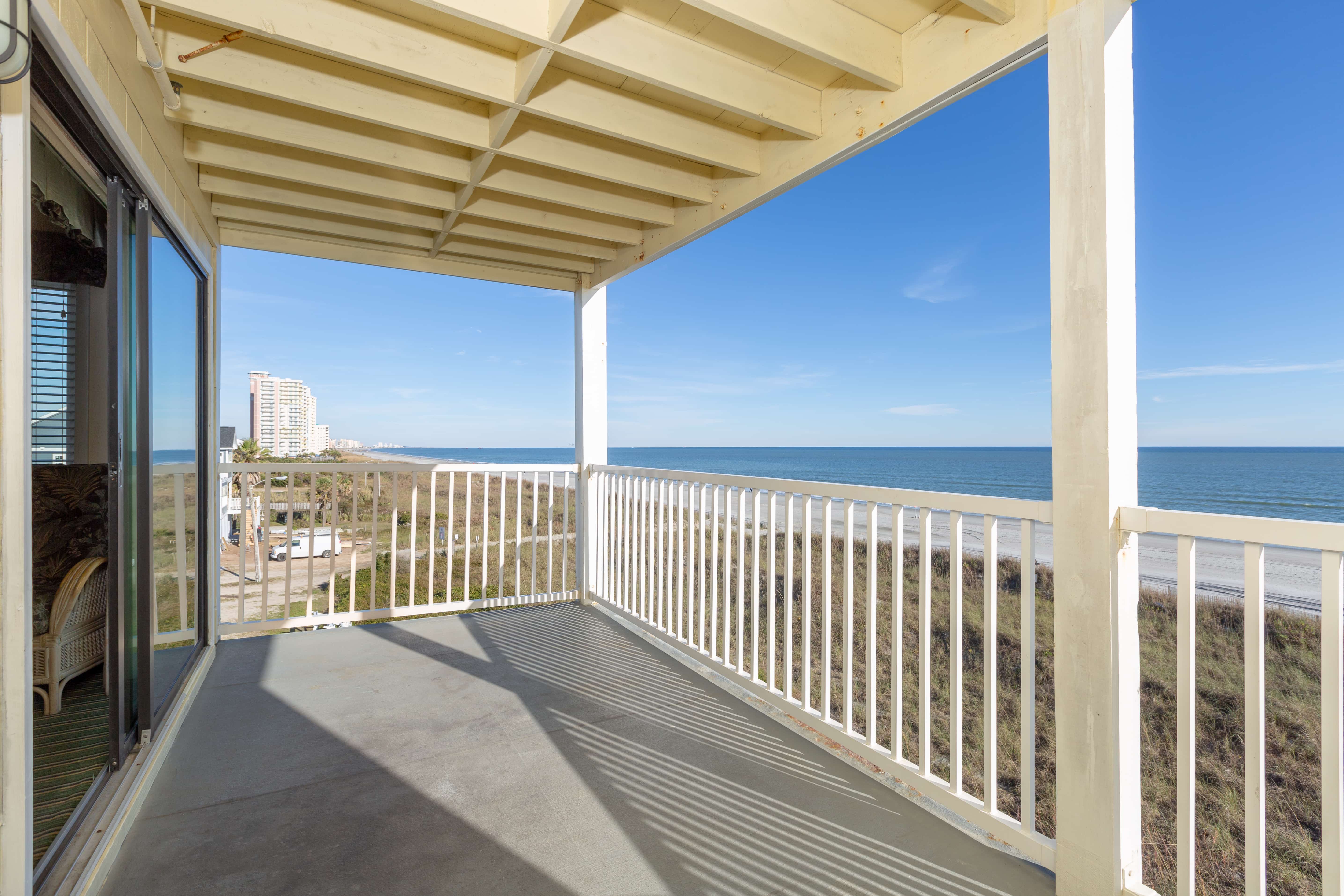 A balcony with a white railing and a view of the ocean