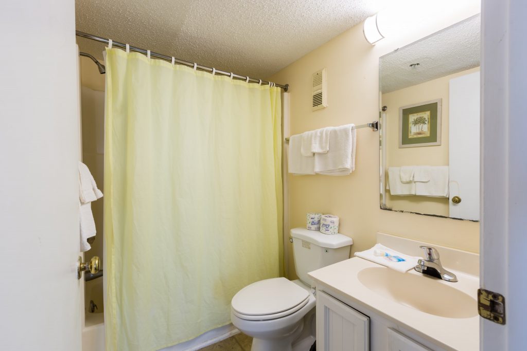 A bathroom with a toilet, sink, shower, and towels.