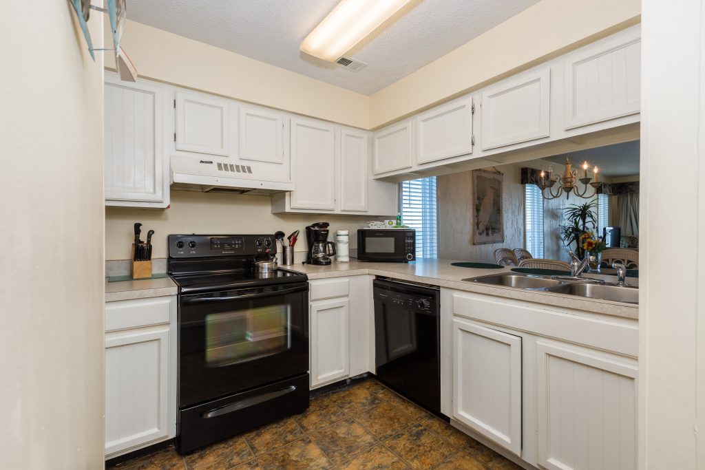 A kitchen with white cabinets and black appliances.
